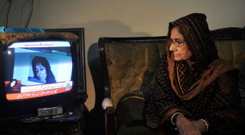 कराची में, आफिया सिद्दीकी की मां, इस्मत सिद्दीकी, अपनी बेटी के खिलाफ अदालत के फैसले के बाद एक समाचार रिपोर्ट देखती है।