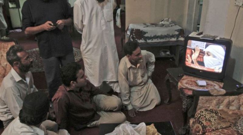 2010 में संयुक्त राज्य अमेरिका में सिद्दीकी के मुकदमे के दौरान पाकिस्तान के कराची में संदिग्ध अल-कायदा के संदिग्ध आफिया सिद्दीकी के घर पर लोग टेलीविजन देखते हैं।