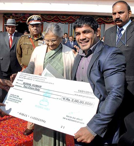 सुशील कुमार रुपये का चेक प्राप्त करते हुए।  दिल्ली की पूर्व सीएम शीला दीक्षित से 2 करोड़