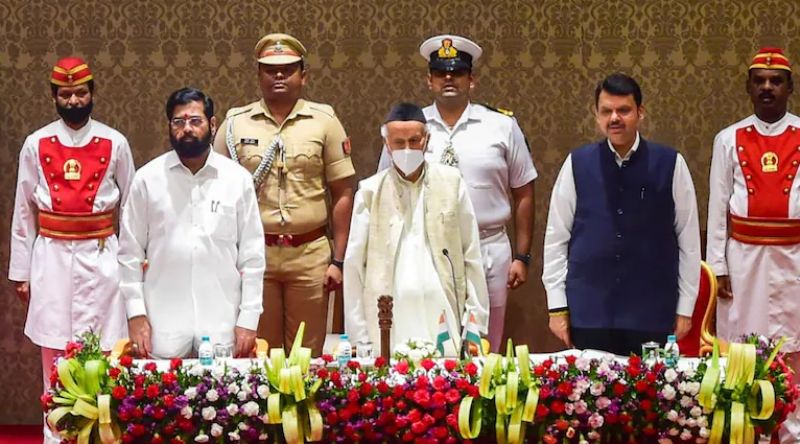 महाराष्ट्र के राज्यपाल (केंद्र), सीएम एकनाथ शिंदे (बाएं) और डिप्टी सीएम देवेंद्र फडणवीस (दाएं) 30 जून, 2022 को राजभवन की पृष्ठभूमि में राष्ट्रगान बजने के साथ खड़े हैं